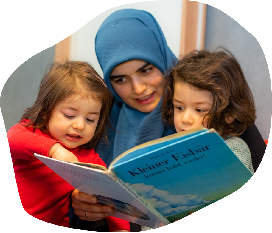 Zusammen lesen mit Kindern Frau liest zwei Kindern aus Buch vor.